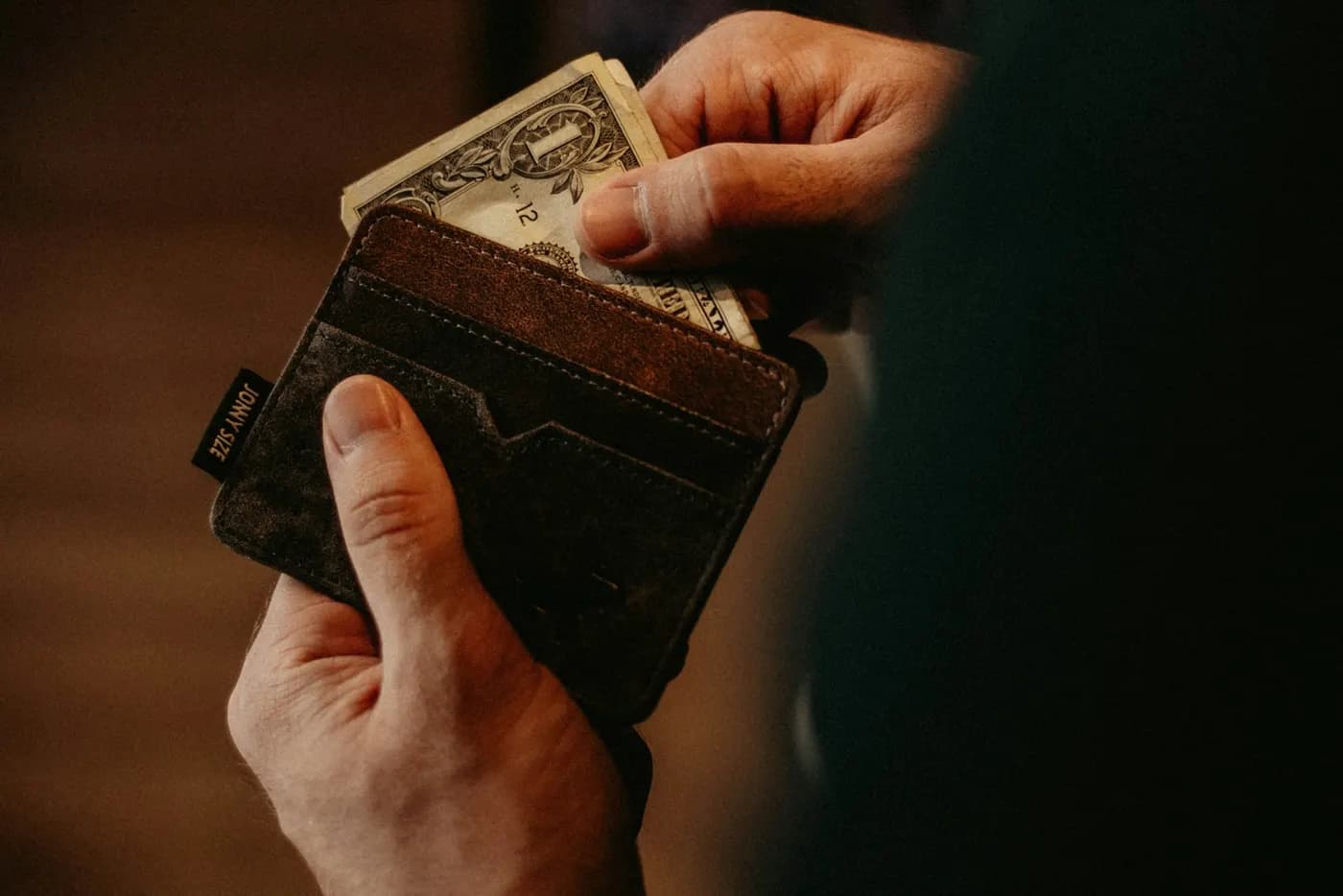 A hand taking US dollar bills from a wallet